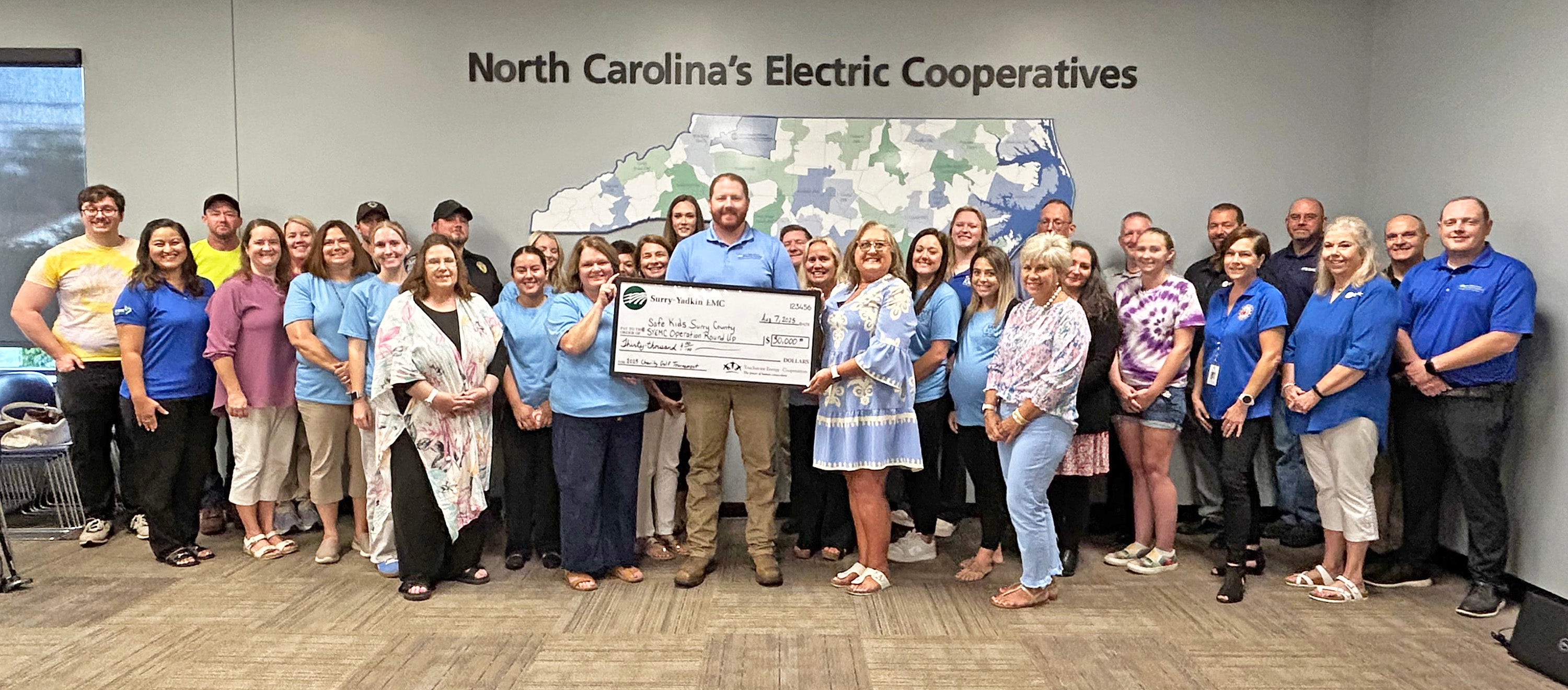 Caleb Lowe, center, along with SYEMC Community Projects Committee members, present a large $30,000 check — a portion of the proceeds raised by SYEMC’s 13th Charity Golf Tournament — to members of the Safe Kids Surry County Coalition and the SYEMC Operation Round Up Board on Thursday, August 7, 2025. Additional funds raised will be used to fund scholarships for community members in the SYEMC service area.